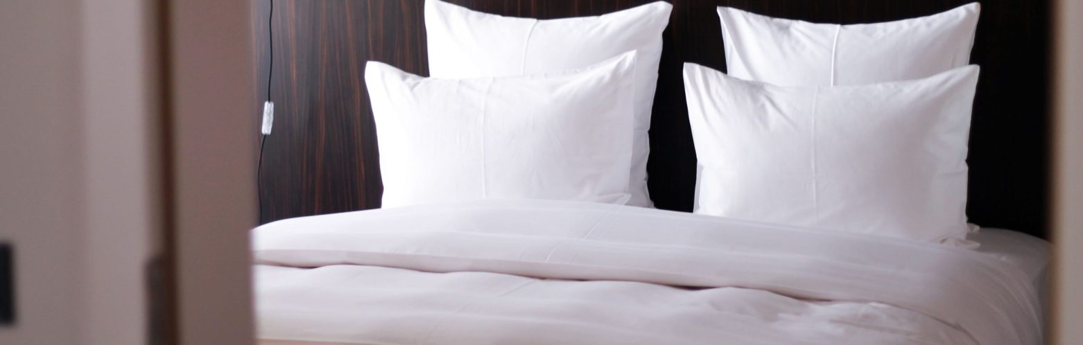 Plush hotel bed with white sheets.