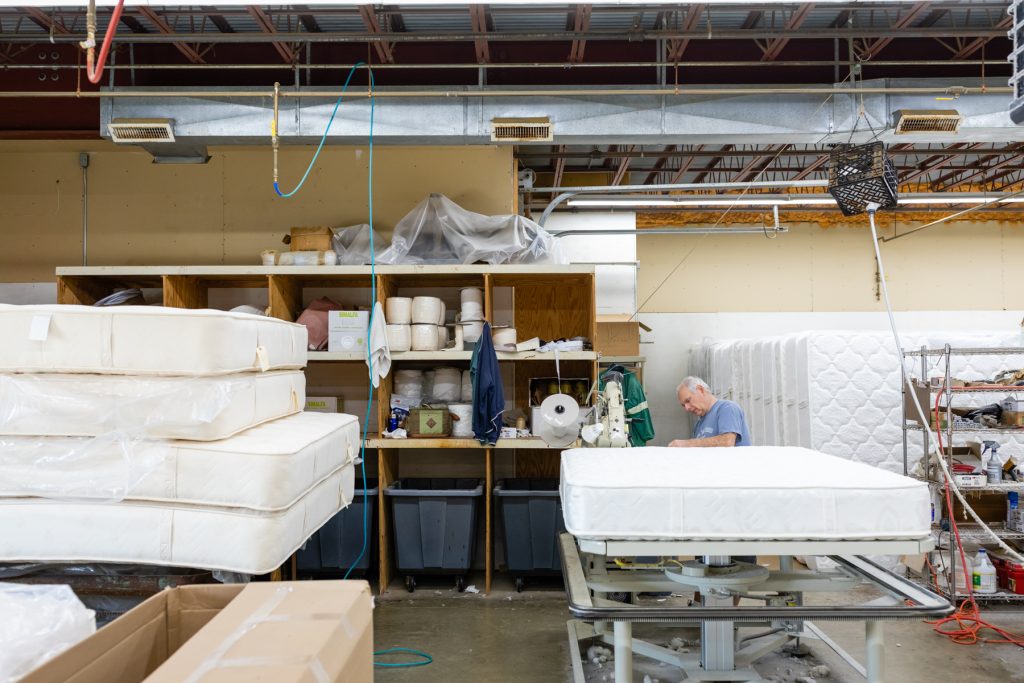 A Gardner Mattress employee hand crafting a mattress in Salem, Massachusetts Showroom