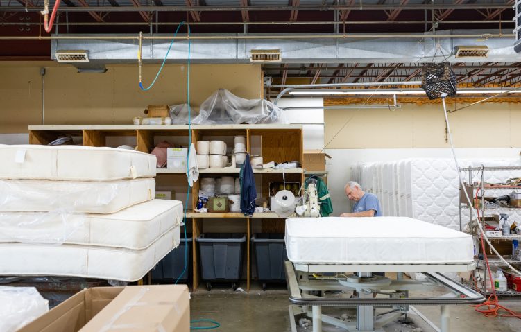 A Gardner Mattress employee hand crafting a mattress in Salem, Massachusetts Showroom